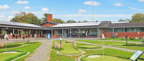 A golf course with a clubhouse, a paved walkway, and a well-maintained lawn.