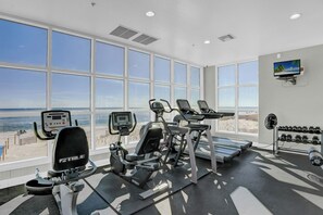A gym with cardio equipment, a treadmill, and dumbbells.