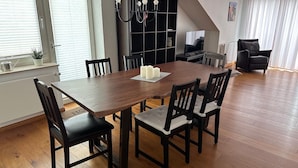 A dining area with a wooden table, six chairs, and a chandelier. - Cozy Apartment With Fireplace and Balcony (Brilon)