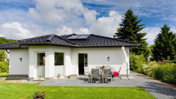 A modern two-story house with a sloped roof, solar panels, and a patio with outdoor furniture. - Apartment in Tisens (Putbus)
