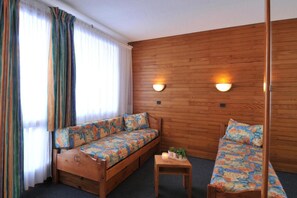 Een gezellige kamer met een houten wand, een bank, een kleine tafel en een stoel.