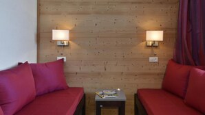 A room with two red sofas, a small table with a magazine, and two wall-mounted lamps. - Ski-in/ski-out & foot of the slopes, 3rd floor, tv, 28m², La Plagne (La Plagne)