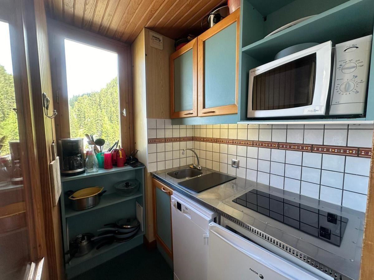 A compact kitchen with a sink, microwave, and wooden cabinets.
