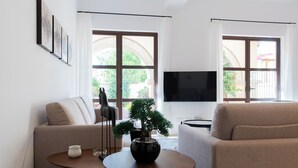Moderni olohuone, jossa on kaksi sohvaa, sohvapöytä, bonsaipuu ja litteänäyttöinen televisio.