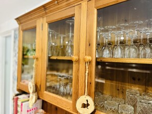 A wooden cabinet with glass doors containing various glassware. - Devon 6-bed Cottage With Country Views & Parking (Tiverton)