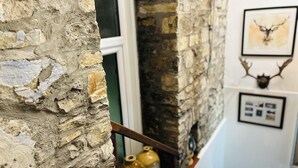 A stone wall with a rustic texture, a window with white framing, and a shelf with decorative vases. - Charming Holiday Cottage in Devon - Country Views (Tiverton)