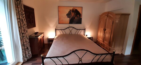Um quarto com uma cama, mesa de cabeceira, cômoda, guarda-roupa e um quadro na parede.