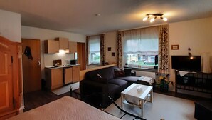Ett kompakt bostadsutrymme med ett litet kök, en soffa, ett soffbord och en TV.