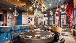 Una zona de bar con una mesa redonda, taburetes de bar y una variedad de botellas.