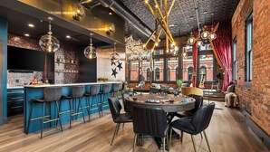 Un área de bar moderna con una mesa redonda, taburetes y luces colgantes.