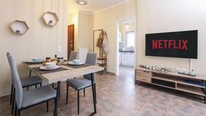 Moderni olohuone, jossa on ruokailutila, televisio, jossa näkyy Netflix, ja naulakko.