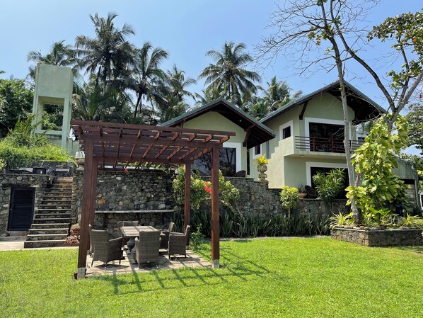 Una casa con una escalera de piedra, una pérgola de madera y un césped.