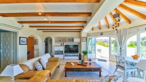 A spacious living room with a sofa, coffee table, and a TV in the background. - Casa Palmeras - Moraira (Moraira)