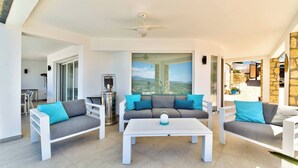 An outdoor patio area with a white sofa, a white coffee table, and a ceiling fan. - Casa Palmeras - Moraira (Moraira)