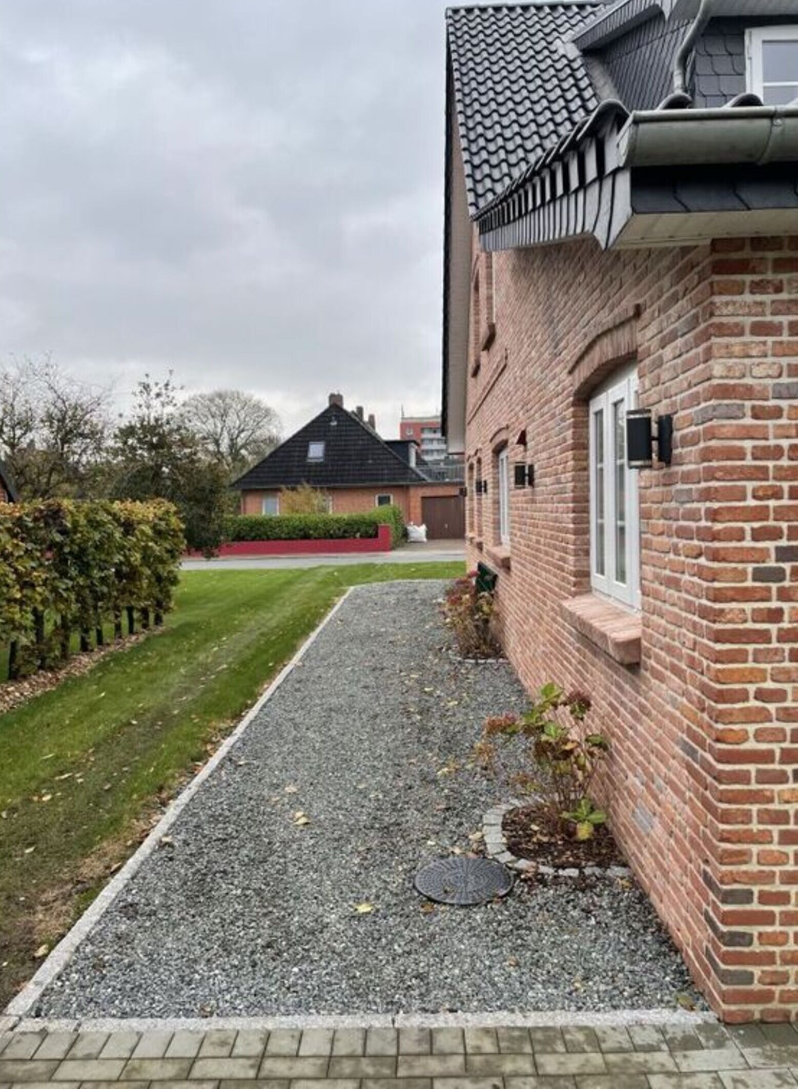 Ein Wohnhaus mit Backsteinfassade, einem Kiesweg und einem gepflegten Rasen.