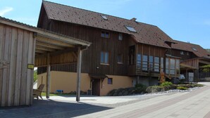 A wooden building with a tiled roof, a covered porch, and a paved walkway. - Csilla Comfortable Holiday Residence (Kaltennordheim)
