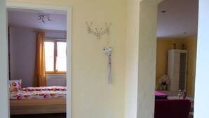 A bedroom with a bed, a nightstand, a mirror, and a window with curtains. - Csilla Comfortable Holiday Residence (Kaltennordheim)