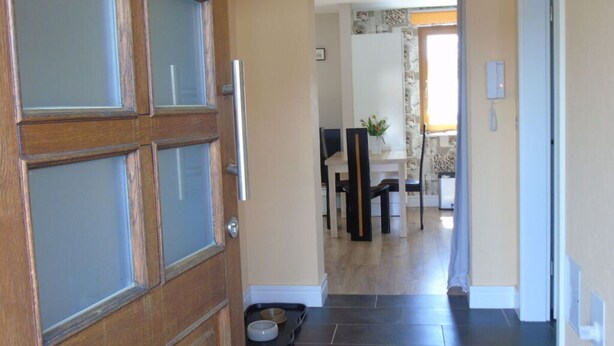 A wooden door with frosted glass panels, leading to a dining area with a table, chairs, and a pet feeding station. - Csilla Comfortable Holiday Residence (Kaltennordheim)