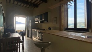 Una cocina con una isla grande, sillas de madera, una mesa de comedor y vista al mar a través de una ventana.