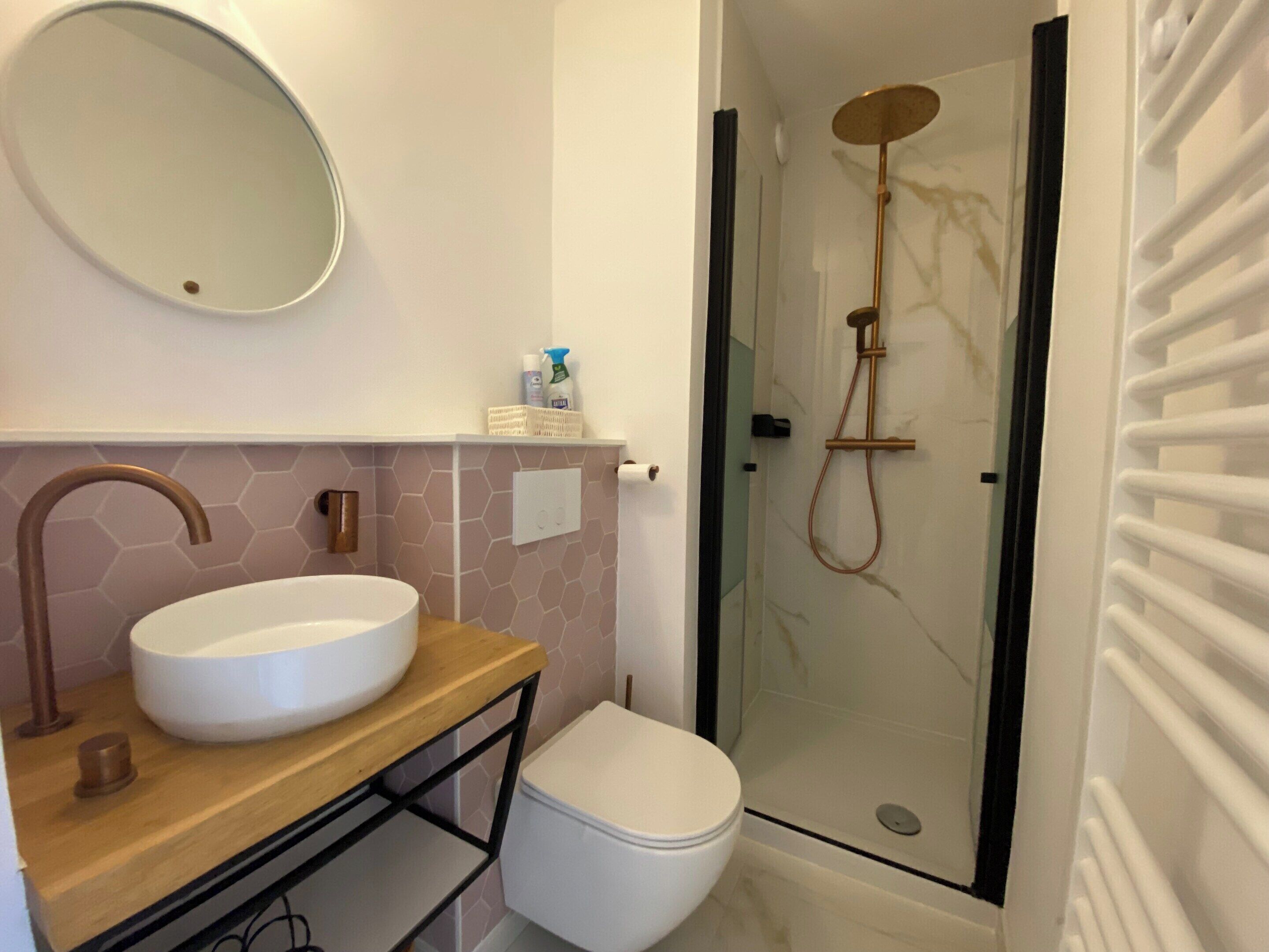 A bathroom with a round sink, a toilet, and a glass-enclosed shower.