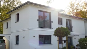 A two-story white building with a small tree in the front yard.