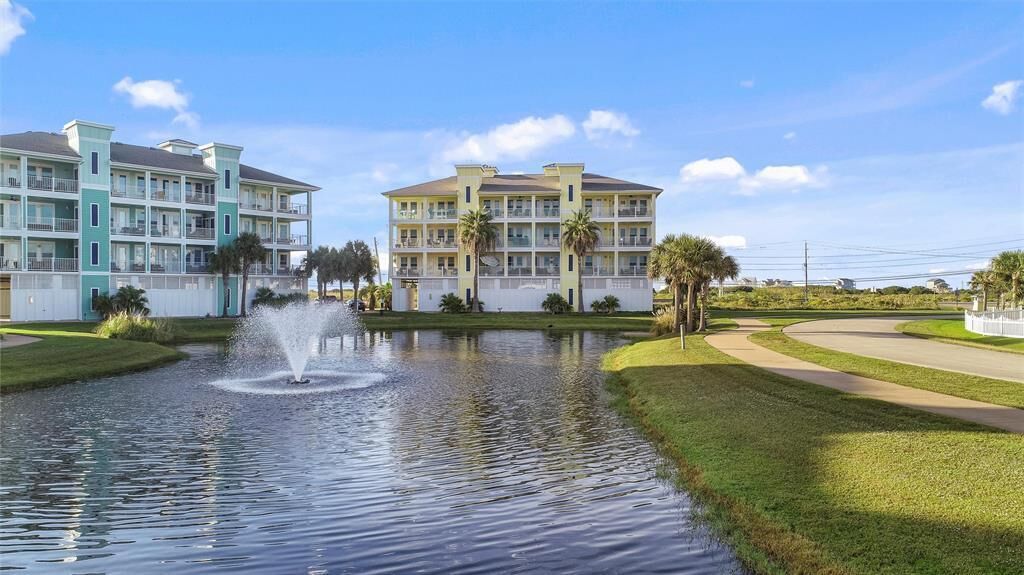 Een hotel met een waterfontein in de binnentuin, omringd door groen en palmbomen.