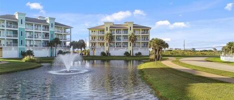 Een hotel met een waterfontein in de binnentuin, omringd door groen en palmbomen.