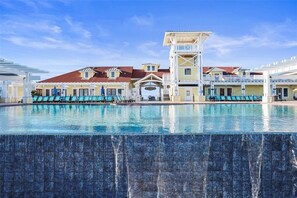 A hotel with a large swimming pool, multiple lounge areas, and a prominent tower structure.