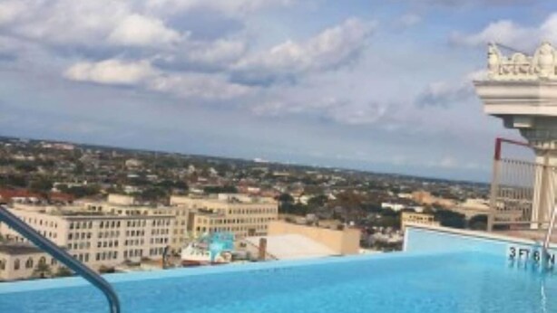 Ein Pool mit Blick auf eine Stadtlandschaft und ein Gebäude mit einer Statue.