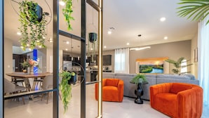 A modern living room with a sofa, chairs, and a dining area with a table and chairs.