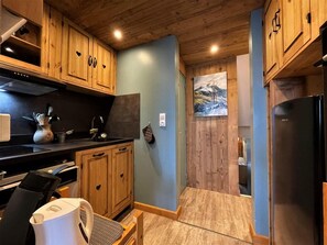 A compact kitchen with wooden cabinets, a black countertop, and a stainless steel refrigerator. - 30m from ski slopes, 3rd floor, balcony, tv, ski locker, 32m², Les Menuires (Les Menuires)