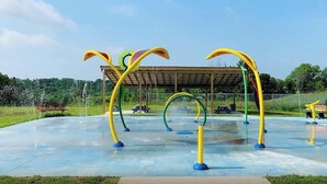 An outdoor playground with colorful climbing structures and a covered seating area.