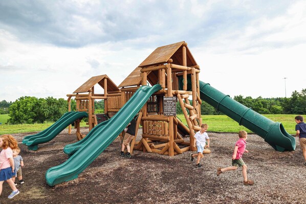 A wooden playground structure with slides and climbing elements.