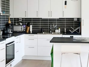 A modern kitchen with white cabinets, a black countertop, and a built-in oven. - 4 Star Holiday Home in Frillesas (Frillesas)