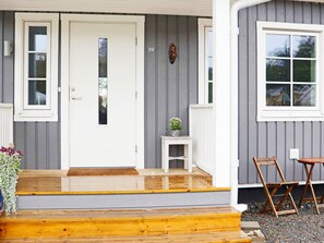 A house with a white front door, a small porch with steps, a mailbox, and a number '20' on the wall.