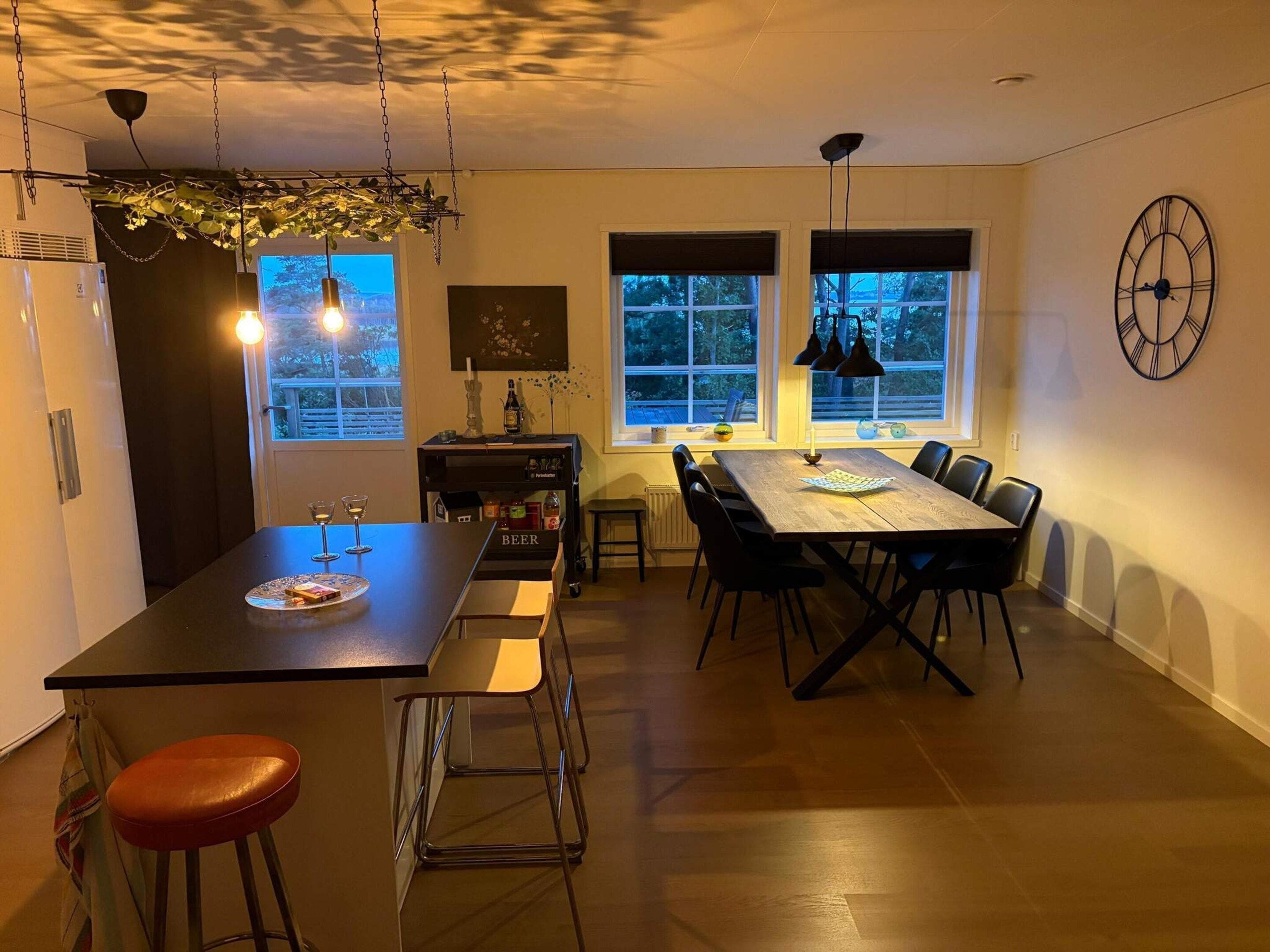 A modern kitchen with a central island, dining table, and bar stools.