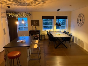 A modern kitchen with a central island, dining table, and bar stools. - 4 Star Holiday Home in Frillesas (Frillesas)