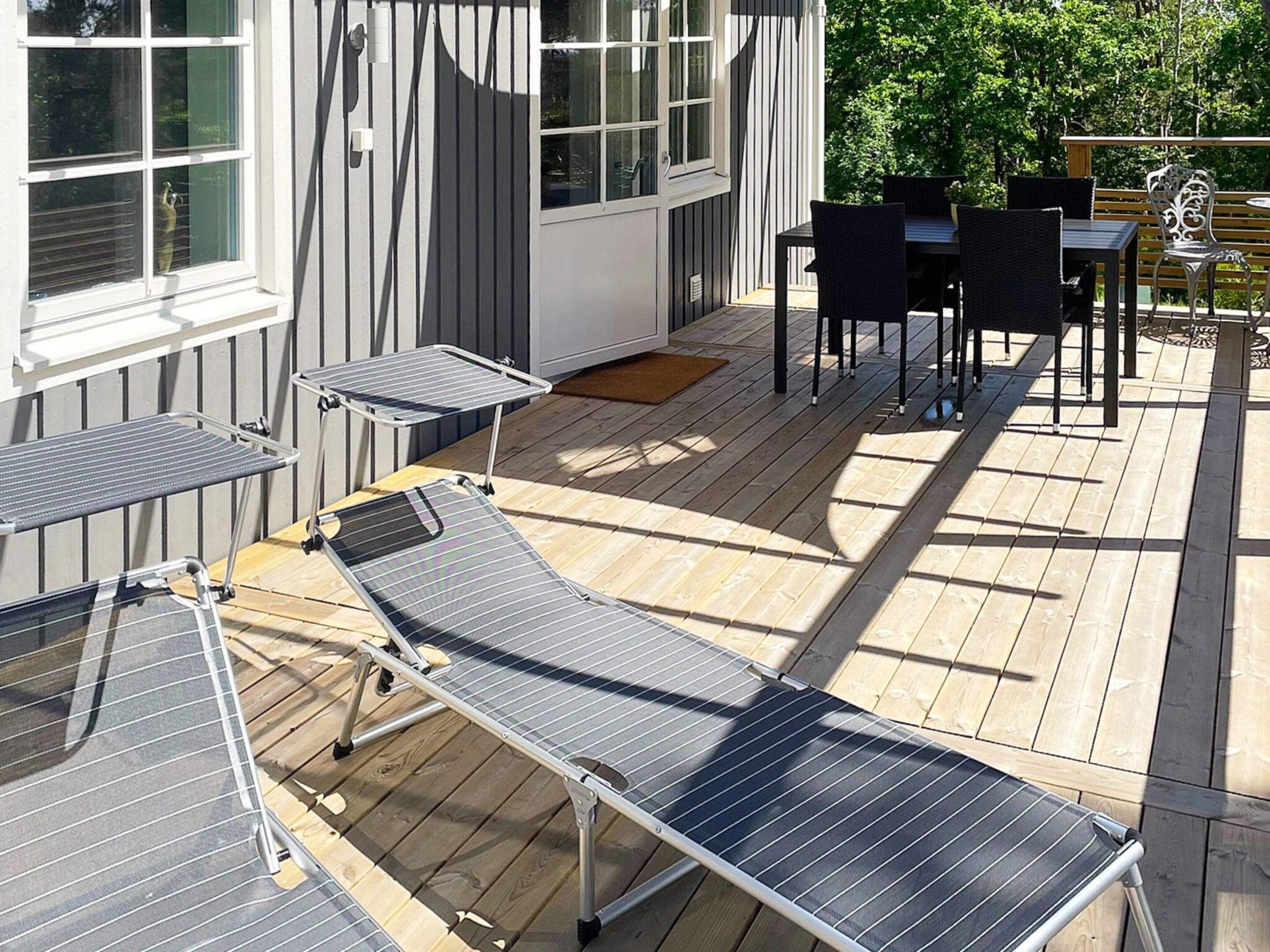 A deck with a table and chairs, a small table with a chair, and a window with blinds.