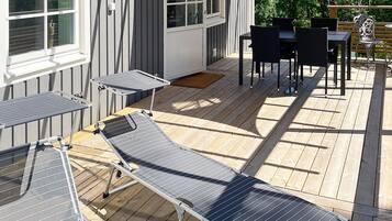 A deck with a table and chairs, a small table with a chair, and a window with blinds.
