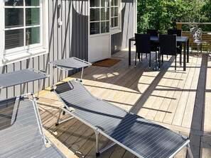 A deck with a table and chairs, a small table with a chair, and a window with blinds. - 4 Star Holiday Home in Frillesas (Frillesas)