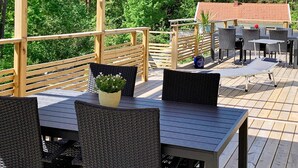 An outdoor deck with wooden railings, wicker furniture, and a table with a potted plant. - 4 Star Holiday Home in Frillesas (Frillesas)