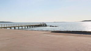 A concrete walkway leading to a pier extending into calm water, with a distant landmass visible. - 4 Star Holiday Home in Frillesas (Frillesas)