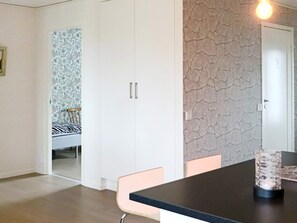 A room with a dining table, chairs, a wardrobe, and a patterned wallpaper. - 4 Star Holiday Home in Frillesas (Frillesas)