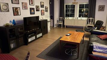 A living room with a TV, sofa, coffee table, and wall art.