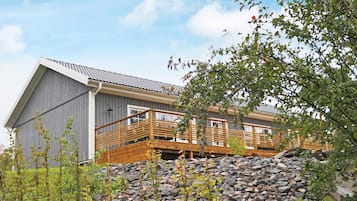A modern building with a wooden deck and a stone wall in front.
