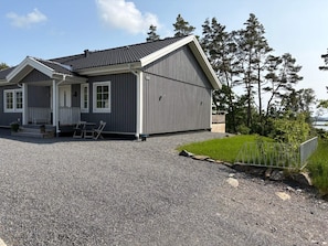 A two-story building with a covered porch, a gravel driveway, and a fenced yard. - 4 Star Holiday Home in Frillesas (Frillesas)