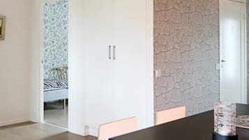 A room with a dining table, chairs, a patterned wallpapered wall, and a door.