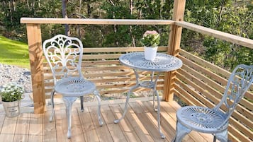 A wooden deck with two metal chairs and a small round table, surrounded by a wooden railing.