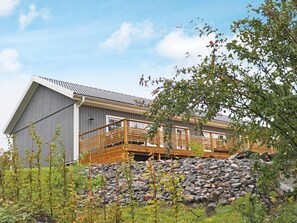 A modern building with a wooden deck, stone wall, and a clear sky. - 4 Star Holiday Home in Frillesas (Frillesas)