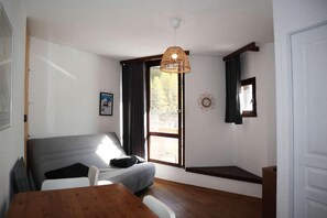 Een kamer met een bed, een tafel, een hanglamp, een raam met gordijnen en een wanddecoratie.